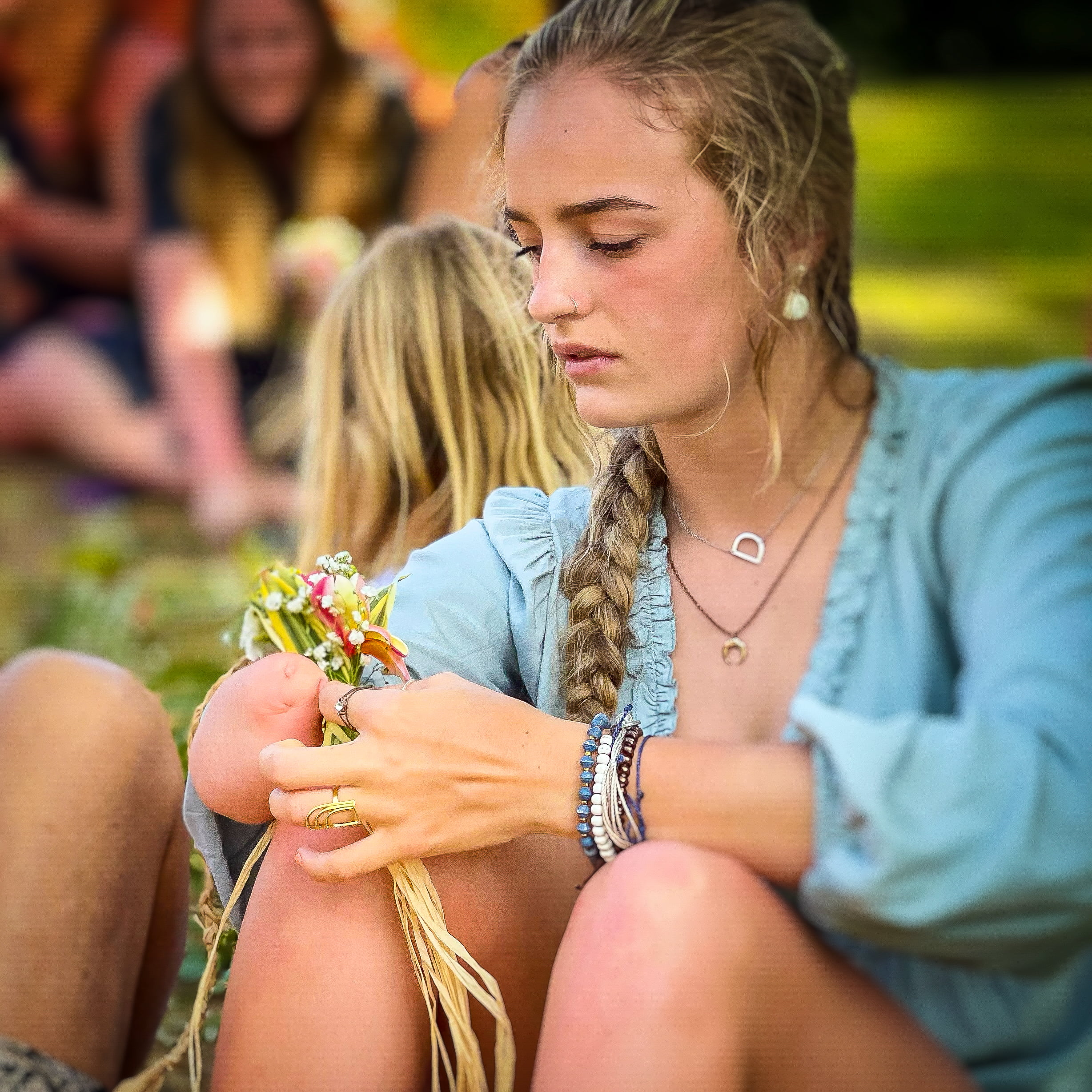 Beautifully Flawed Retreat Attendee Devyn working on her haku lei while wearing her Mae Cargo rainbow ring
