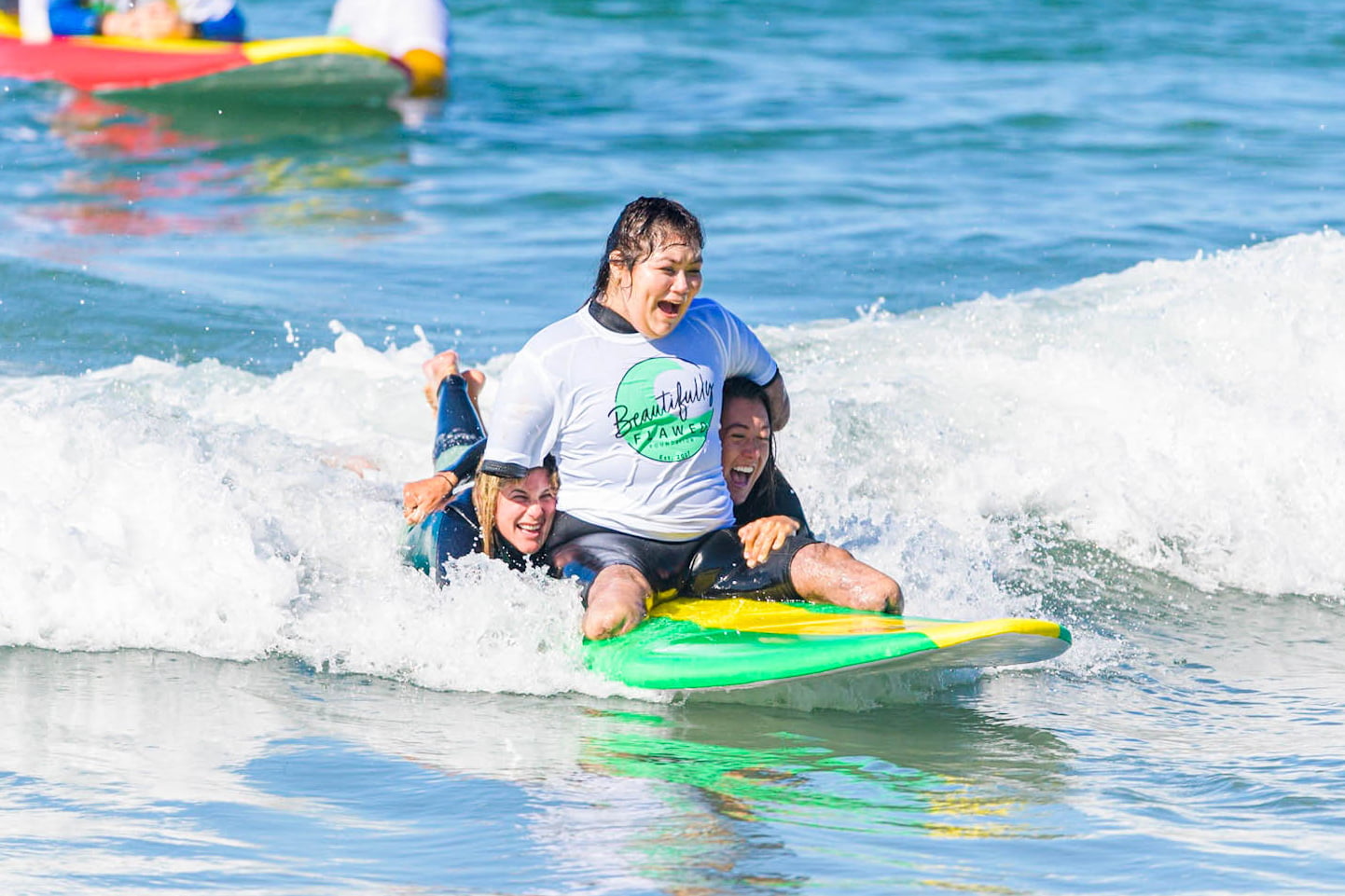 Quad amputee Andrea surfing with the help of our volunteers