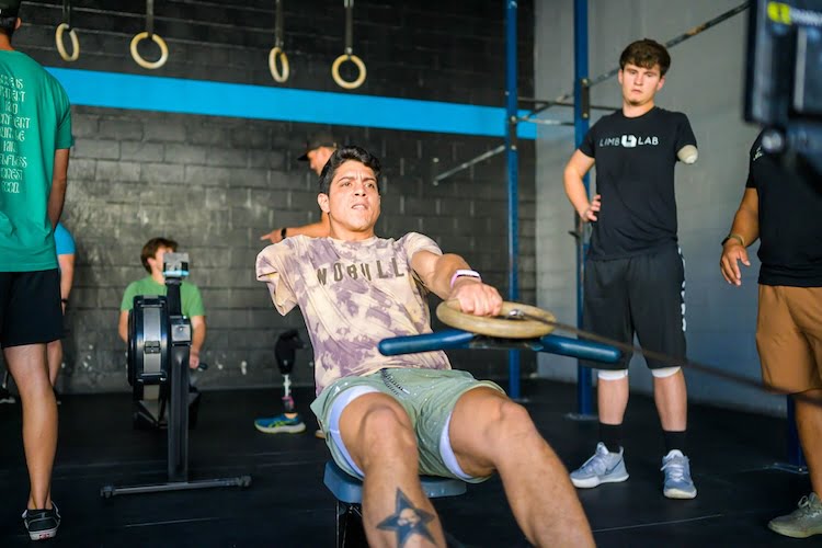Forge attendee Victor uses an adaptive device to row on a rowing machine as an arm amputee.