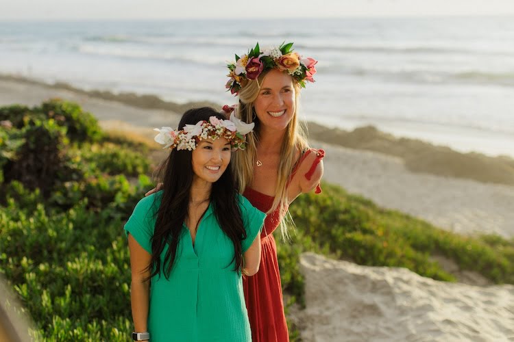 Bethany Hamilton and attendee Sarah smile for a golden hour ocean photo together showing off their arm limb differences.