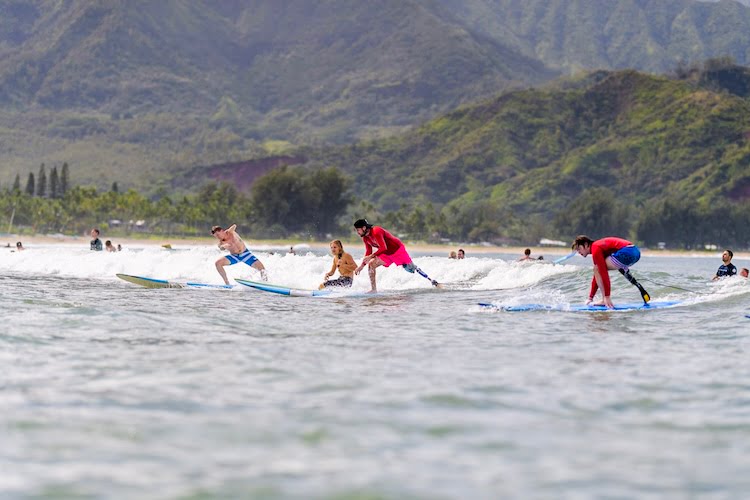 Several Forge men stand up and ride a wave to shore together.