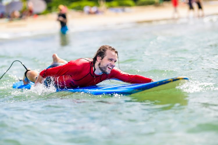 Forge attendee Timo adaptively paddles on his surfboard toward the break.