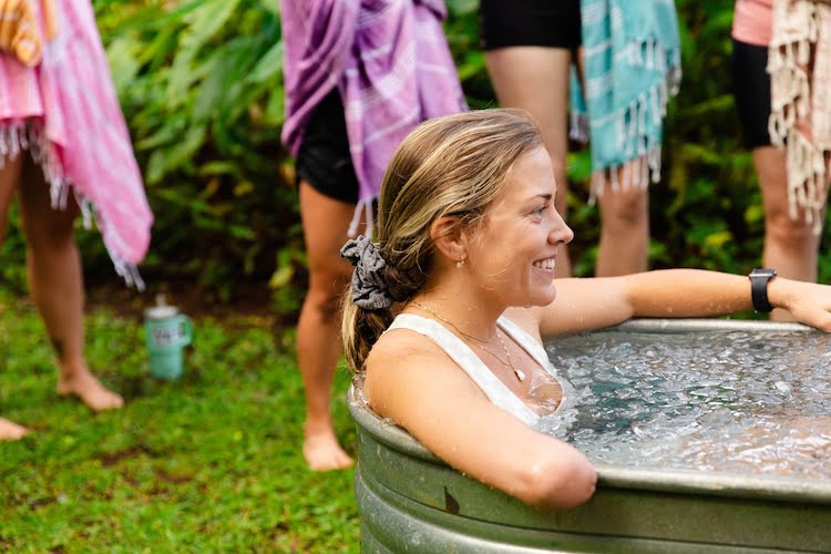 Beautifully Flawed attendee Hannah smiles sitting in the freezing cold water during the ice bath challenge.