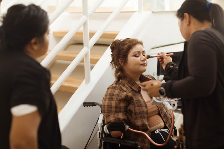 Beautifully Flawed attendee and quad amputee Andrea sits in her wheelchair while getting her makeup professionally done for the individual and group photoshoot to come.